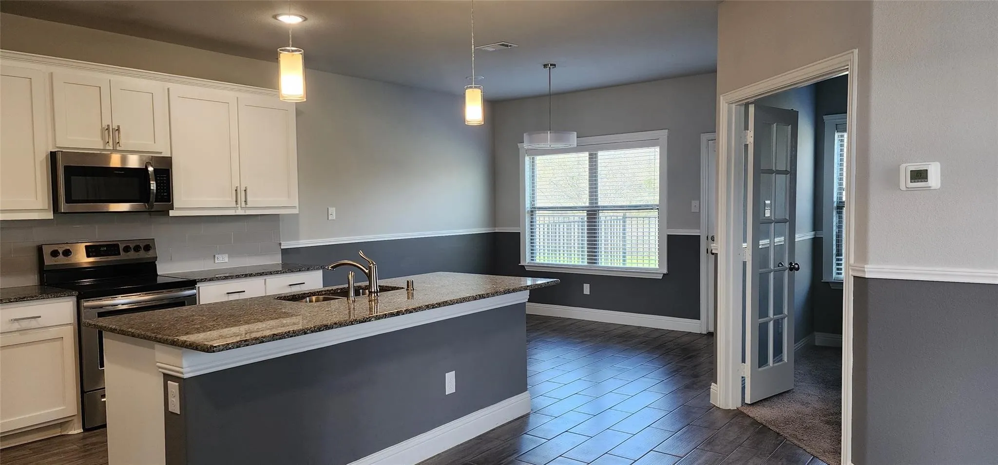 Modern kitchen featuring white cabinetry, stainless steel appliances, and a central island with a double basin sink