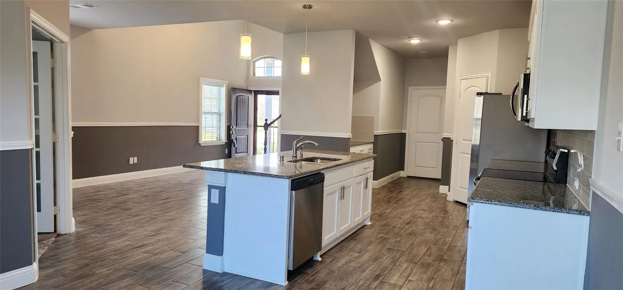 Kitchen island with granite countertop, integrated sink, and stainless steel dishwasher