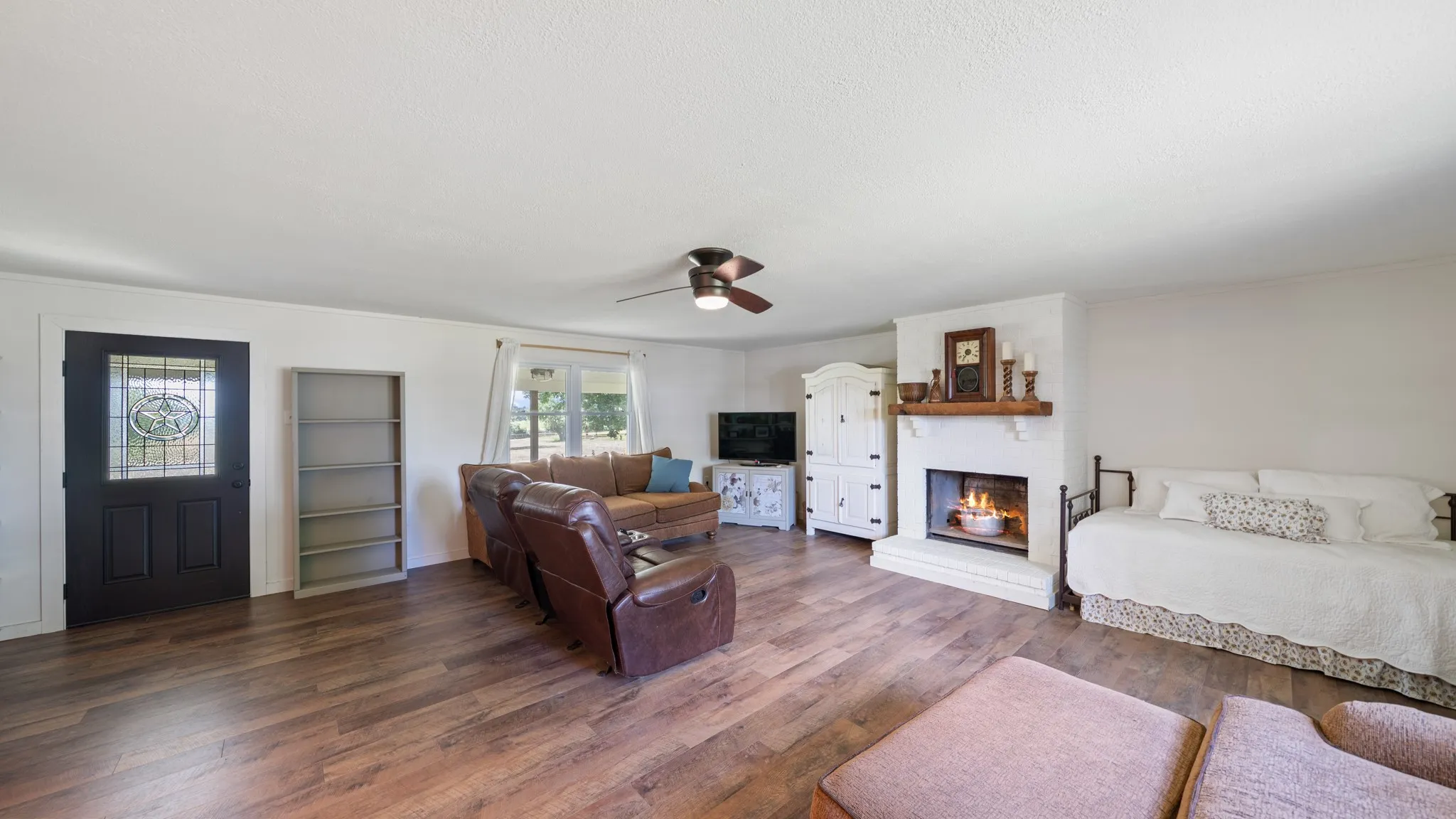 Spacious interior room featuring wood-finish flooring, white walls, and a ceiling fan