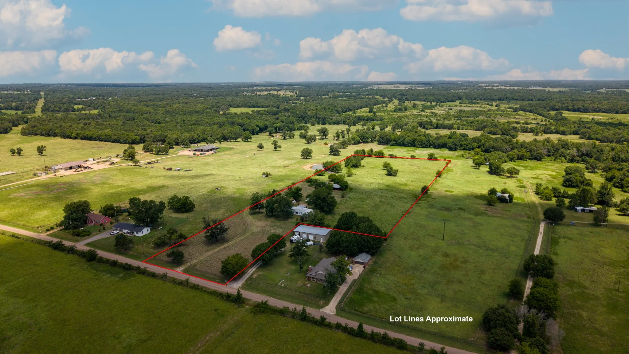 Expansive rural acreage featuring several structures, mature trees, and open fields