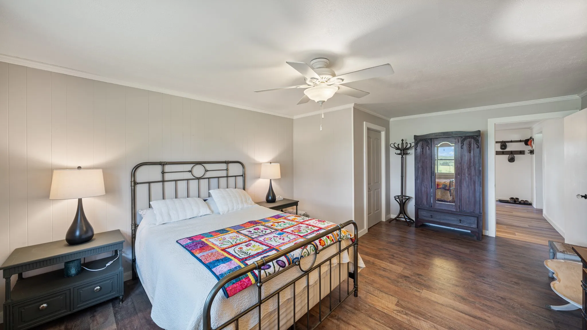 Spacious interior with wood-finish flooring, light gray wall paneling, and a white ceiling fan