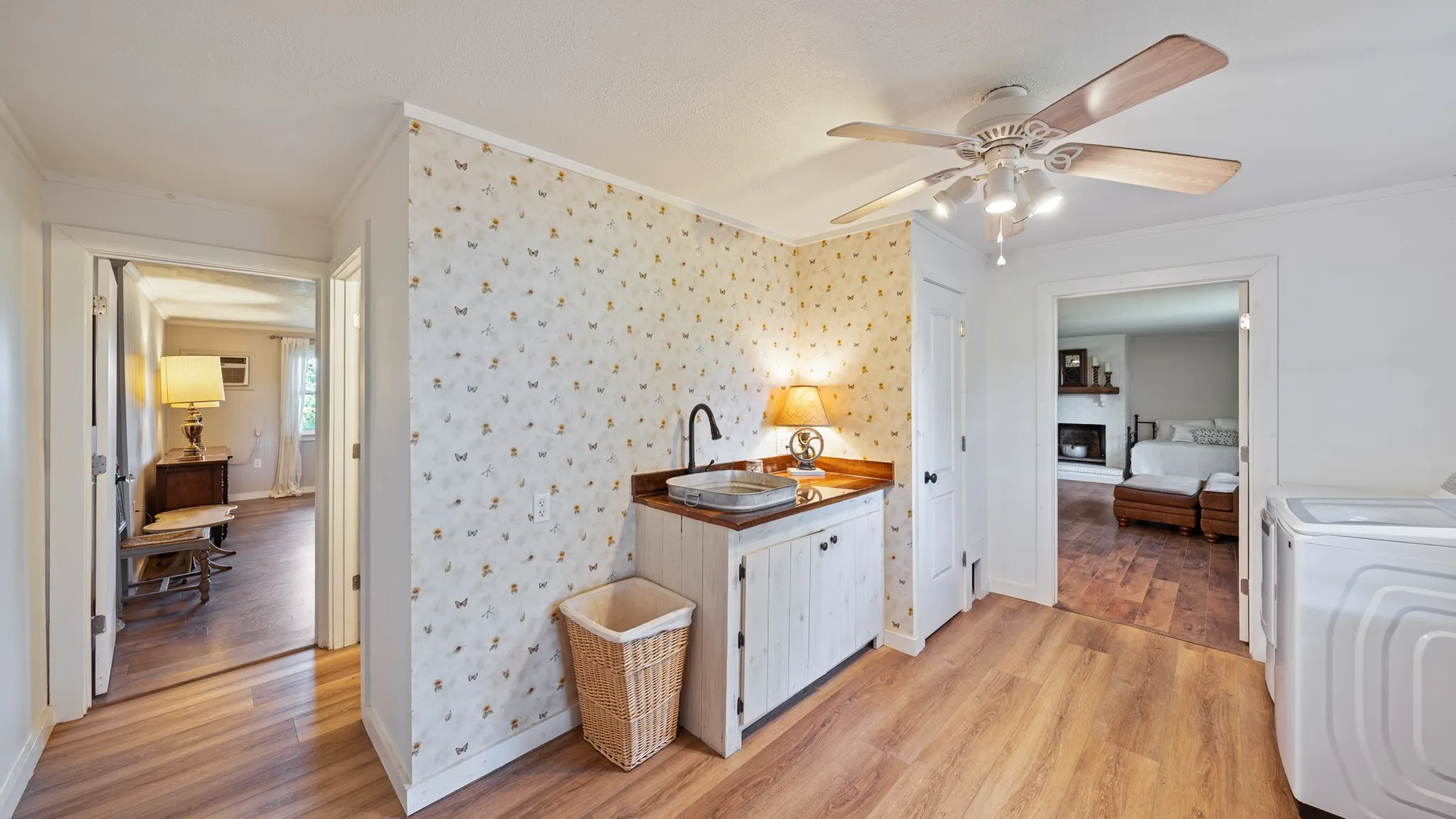 Utility area featuring wood-finish flooring, a ceiling fan with integrated lighting, and a built-in utility sink with a dark-finish faucet