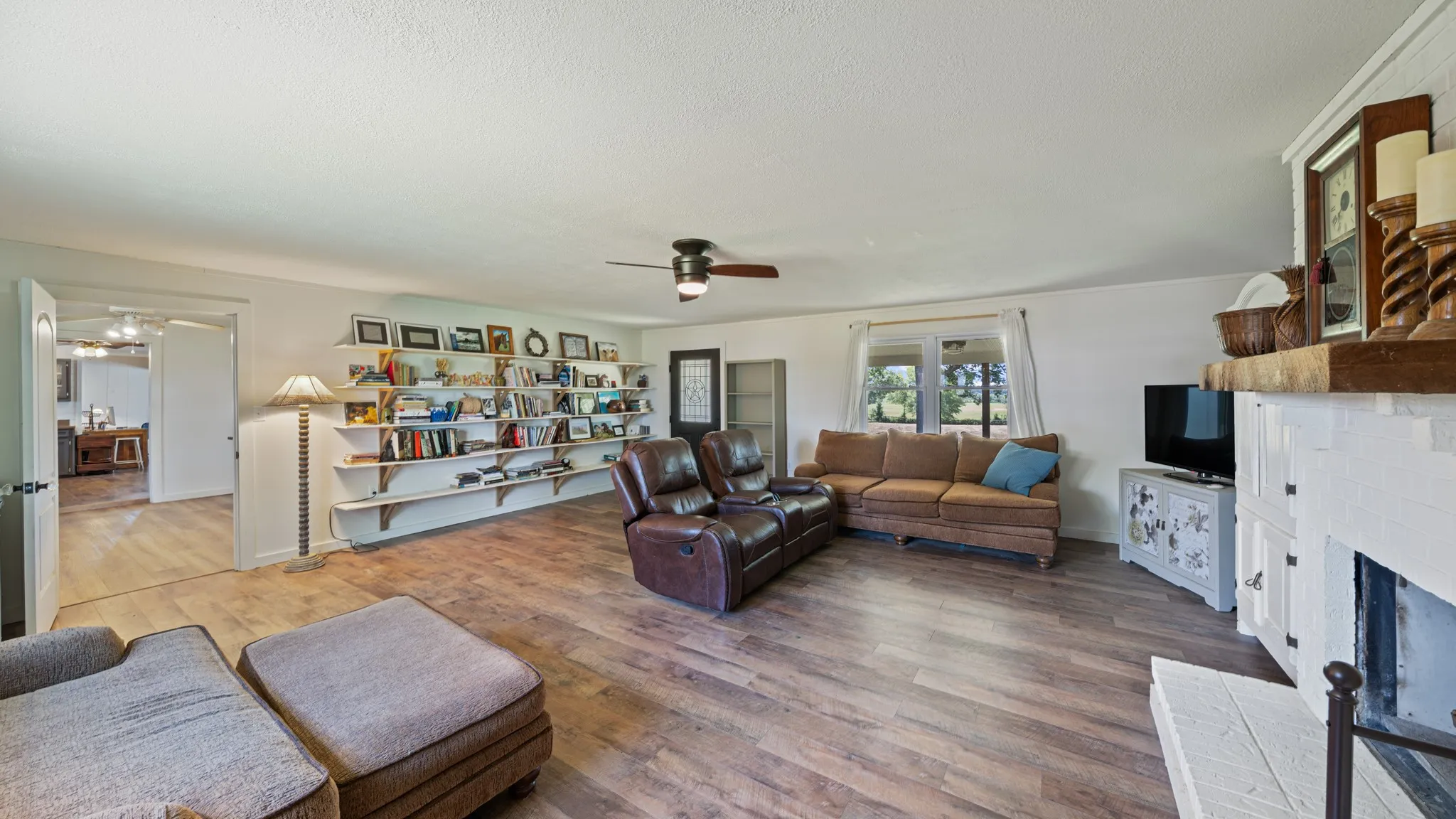 Spacious living area featuring wood-finish flooring, a ceiling fan, and built-in shelving