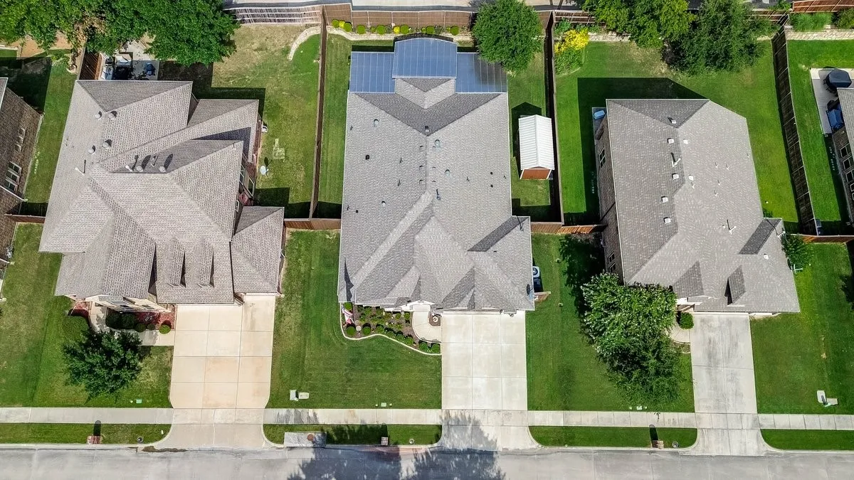 Aerial perspective highlighting three residential properties with gray shingle roofs and concrete driveways