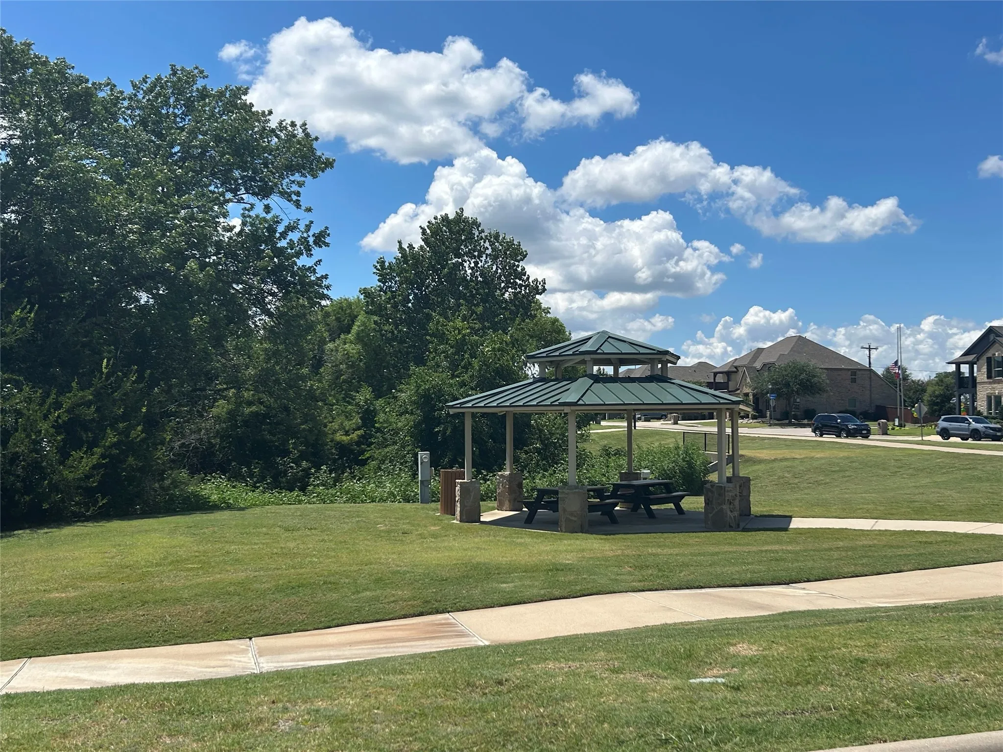Community gazebo with a tiered green roof, stone-clad pillars, and a picnic table