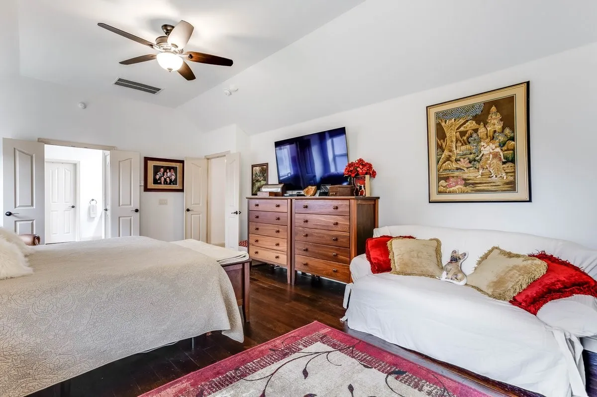 Spacious room featuring vaulted ceilings, dark wood-finish flooring, and white paneled doors