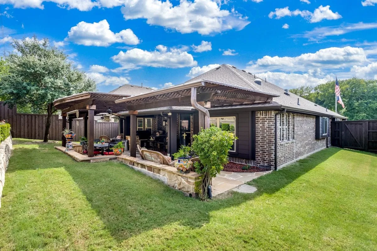Expansive backyard featuring a stone patio, twin pergolas, and a manicured lawn