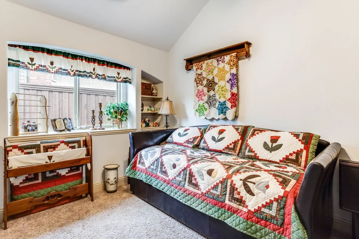 Carpeted room featuring an arched window, a built-in shelving alcove, and a vaulted ceiling