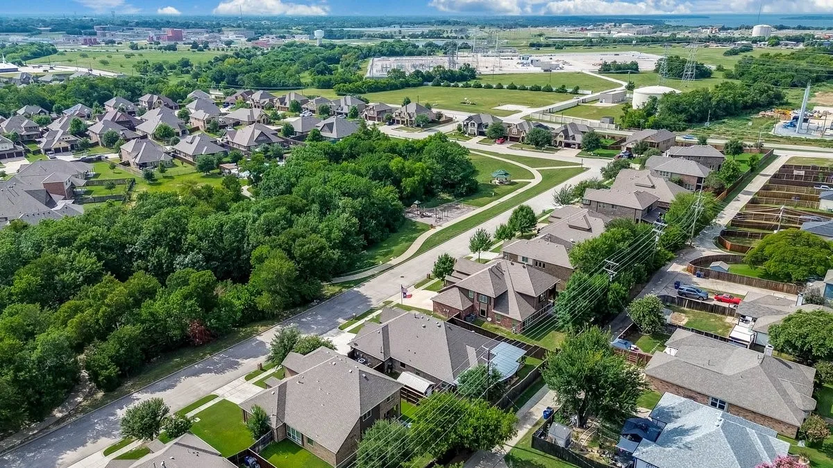 Aerial perspective of a residential neighborhood featuring established homes with gabled roofs, mature trees, and paved streets