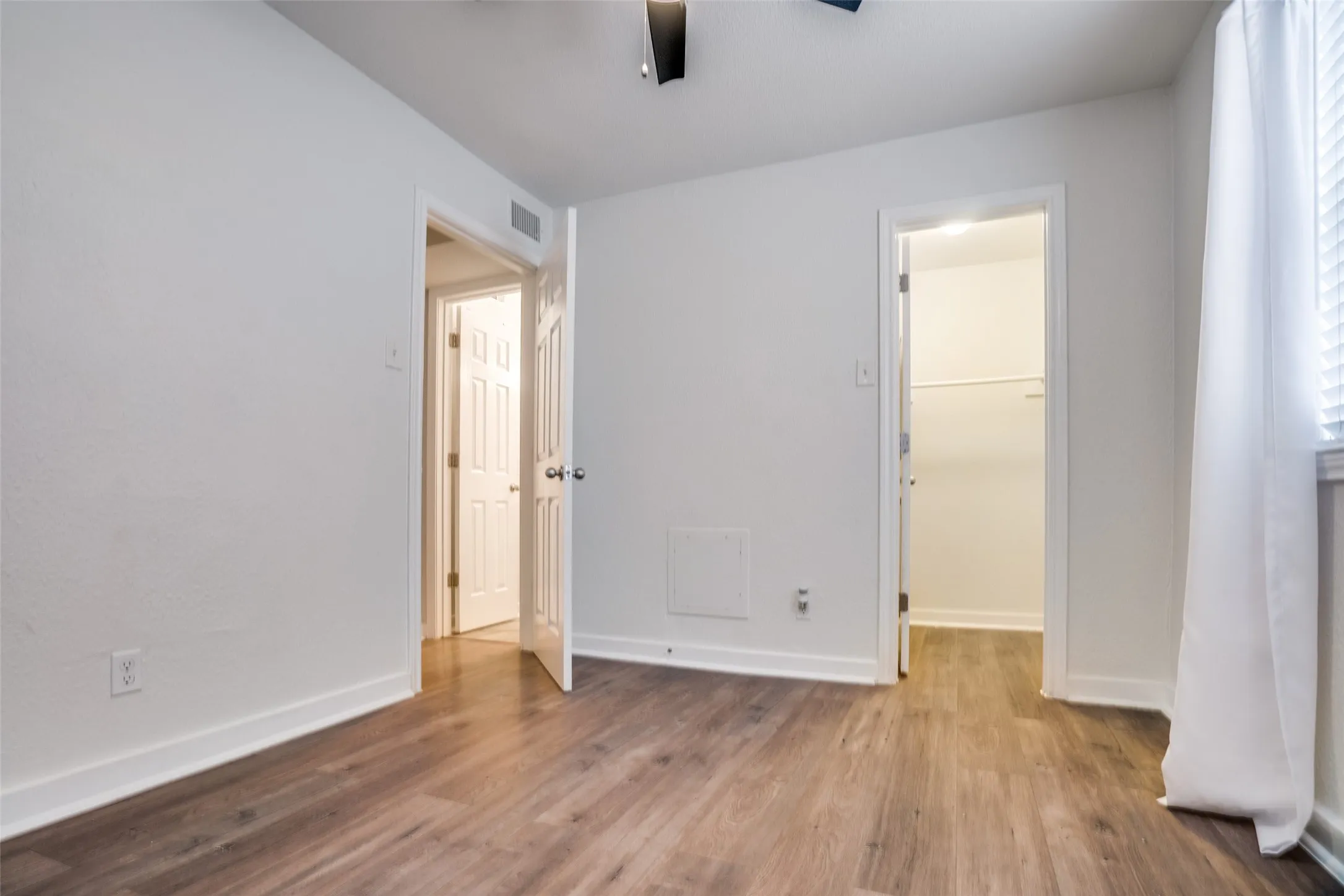 Room featuring wood-finish flooring, white baseboards, and neutral wall paint