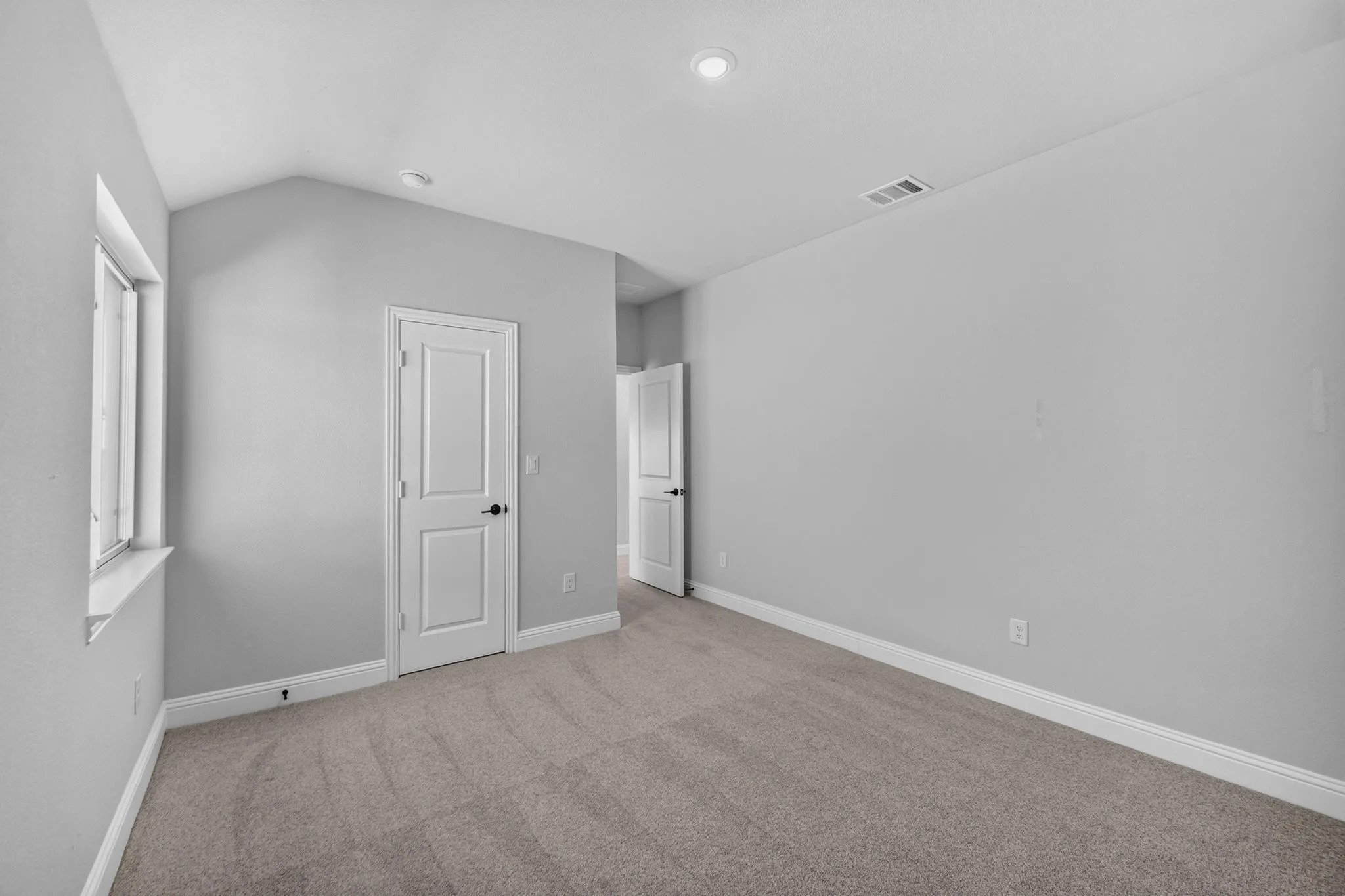 Carpeted room with vaulted ceiling and recessed lighting