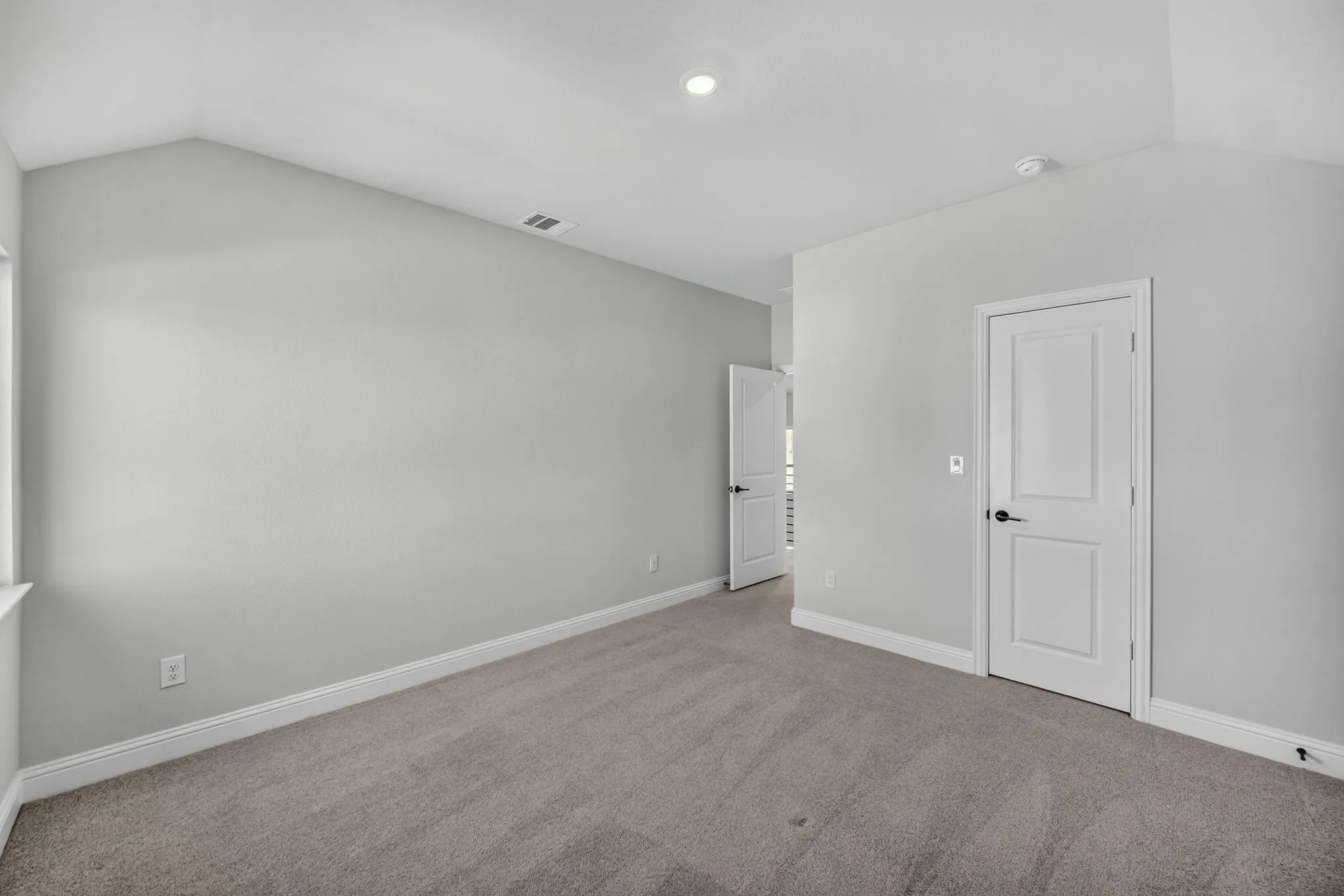 Room featuring vaulted ceilings, light gray wall color, neutral carpet flooring, white trim, and a recessed ceiling light