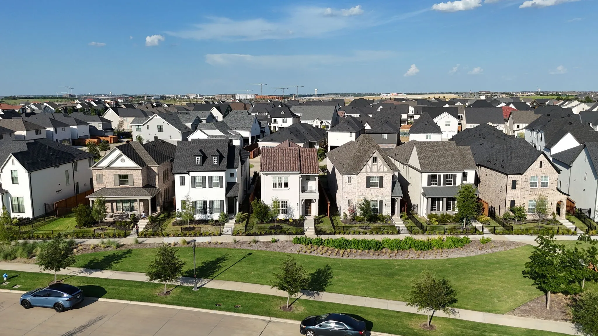 Expansive neighborhood showcasing diverse architectural styles, manicured lawns, paved walkways, and mature landscaping