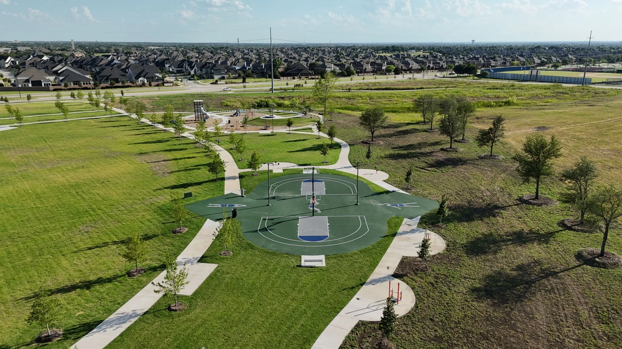 Outdoor recreation area featuring a basketball court, walking paths, and a playground