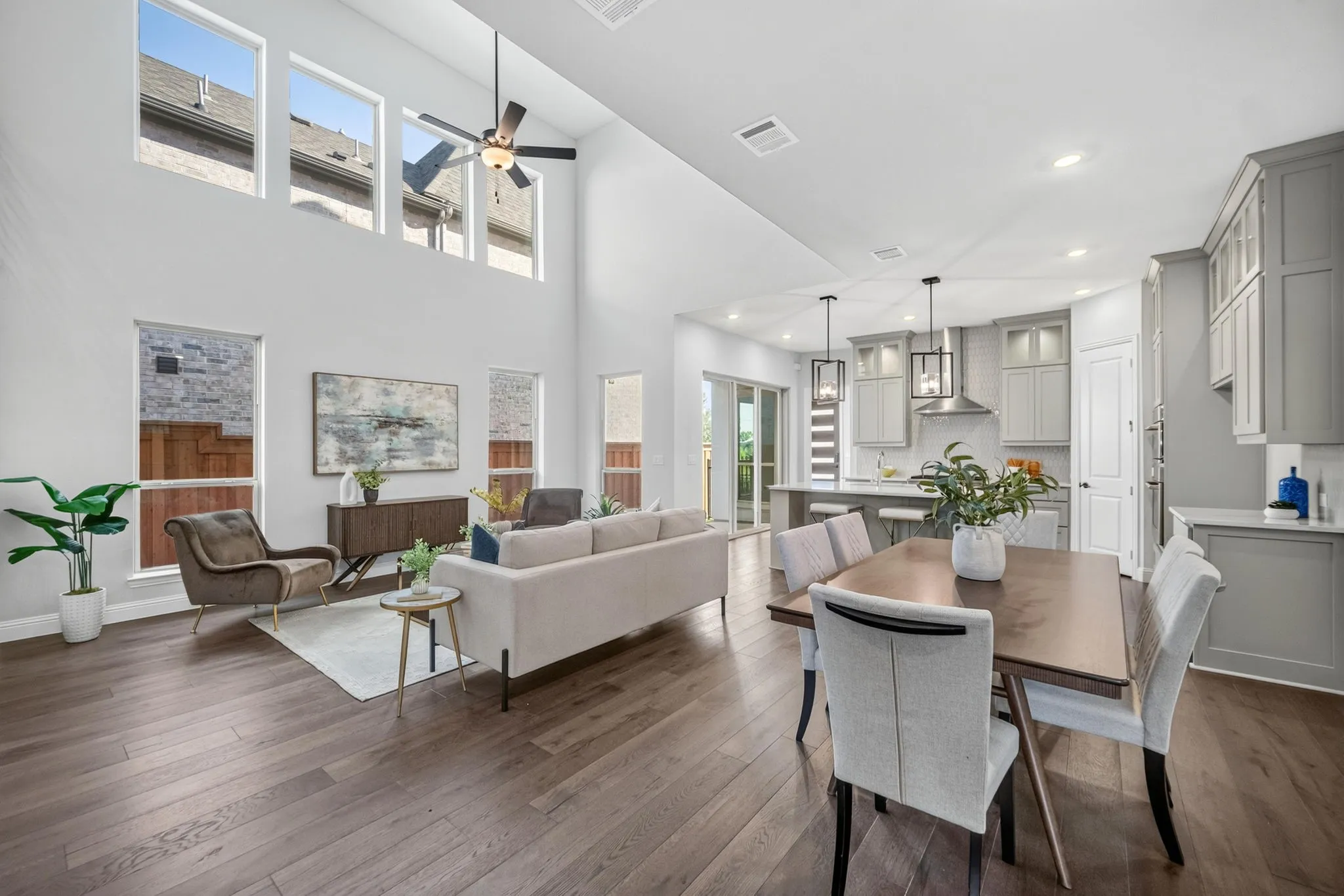Open-concept interior featuring wood-finish flooring, high ceilings with upper windows, and a ceiling fan