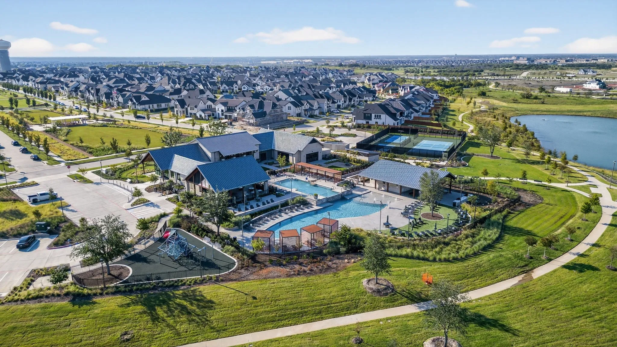 Community amenity center featuring a resort-style pool, multiple covered outdoor lounges, tennis courts, and a dedicated playground area
