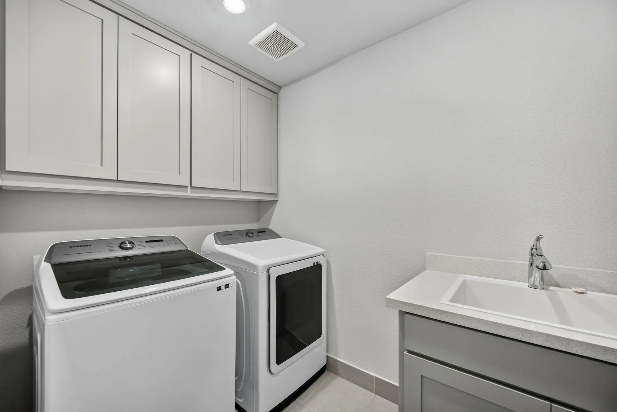 Second floor laundry room featuring light gray cabinetry, a built-in sink with a single-handle faucet, and tile flooring