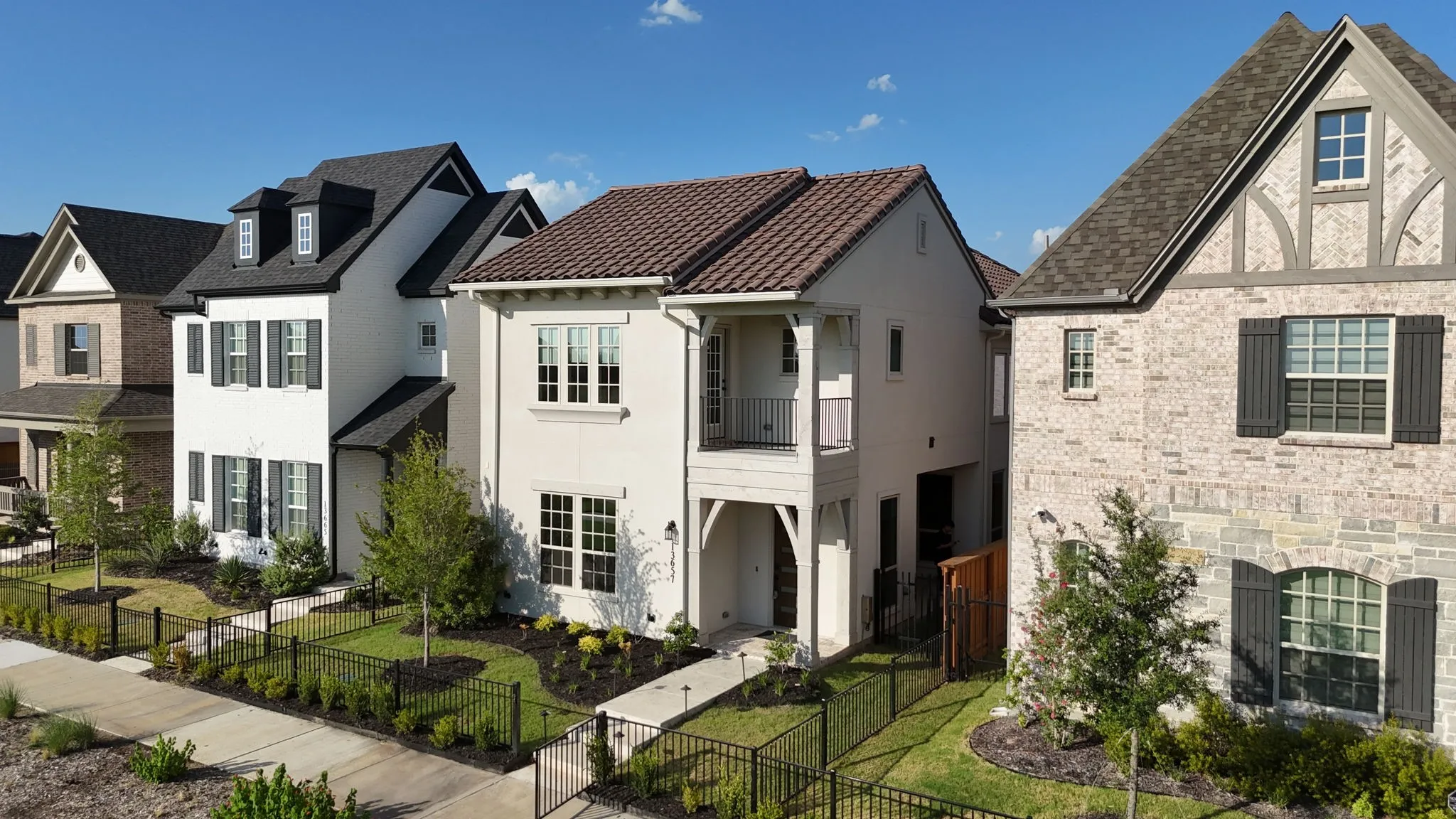 Contemporary stucco exterior featuring a second-story balcony with metal railing, an arched entry, and a tile roof