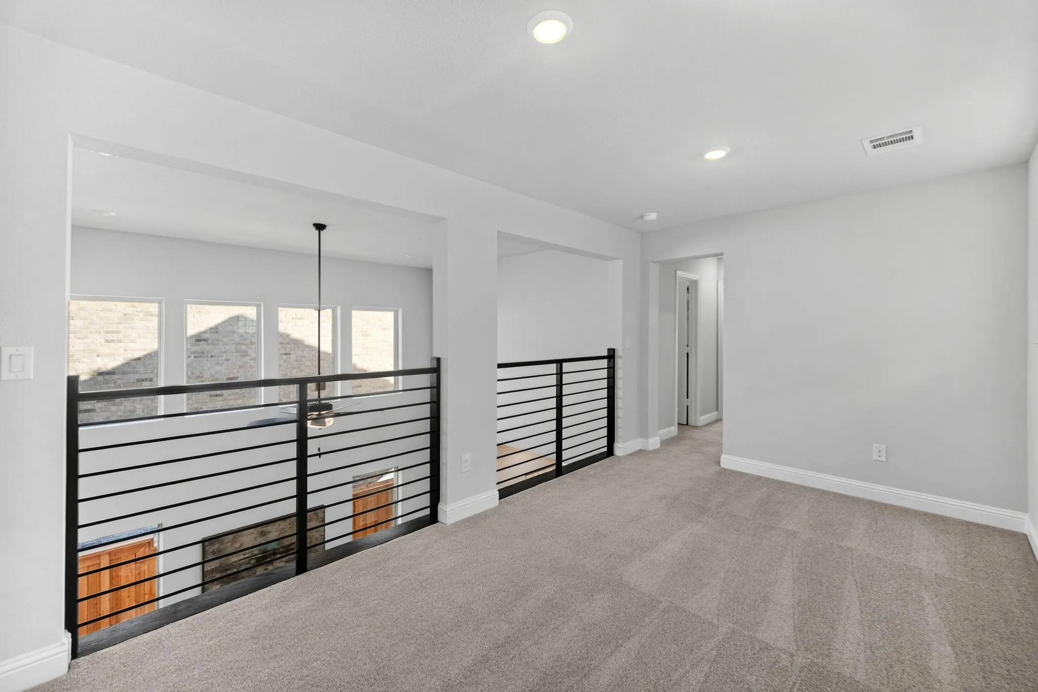 Carpeted loft space featuring contemporary black horizontal railings and white trim