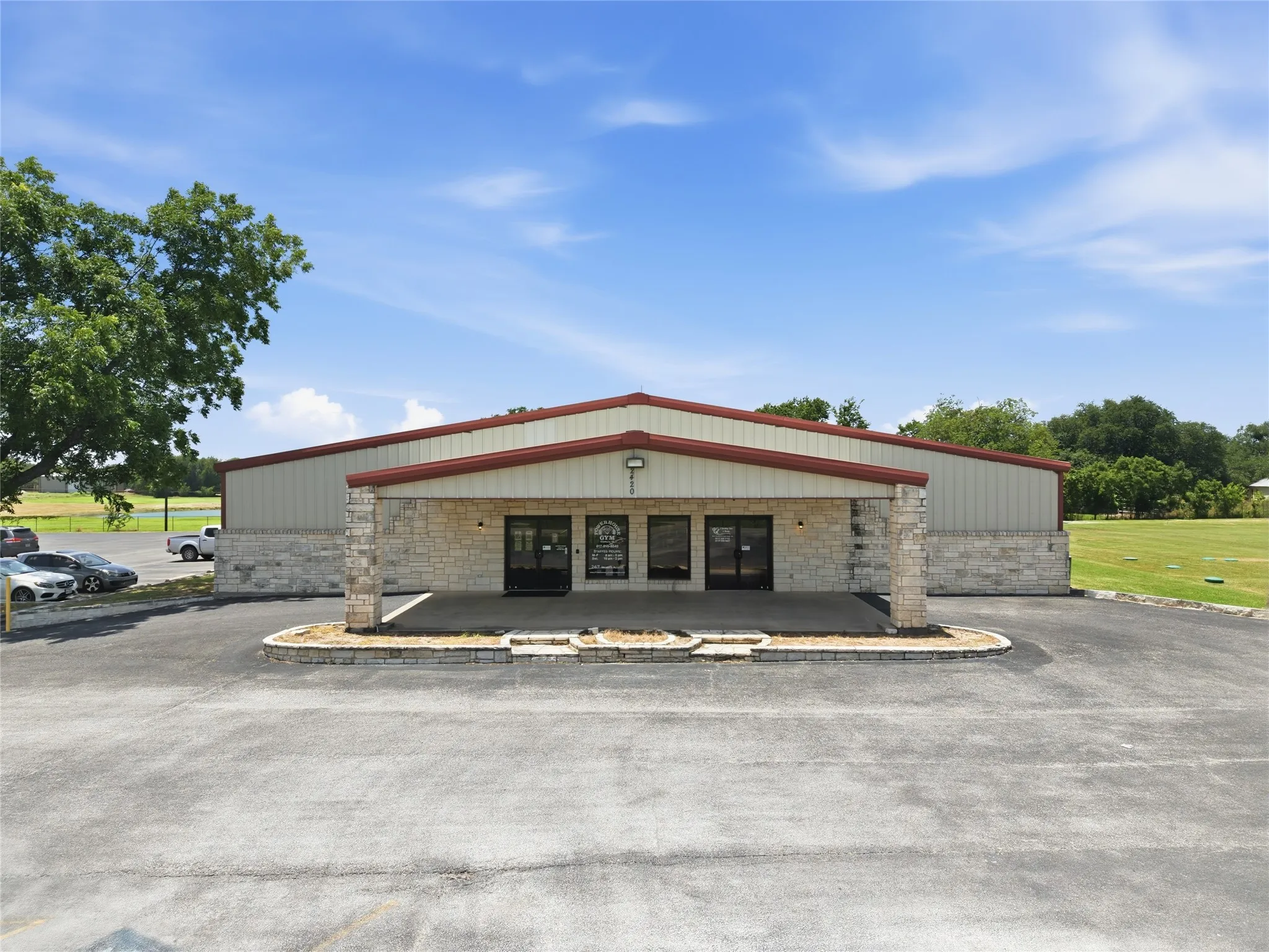 Commercial building featuring a stone facade, red metal roof trim, and a covered entryway
