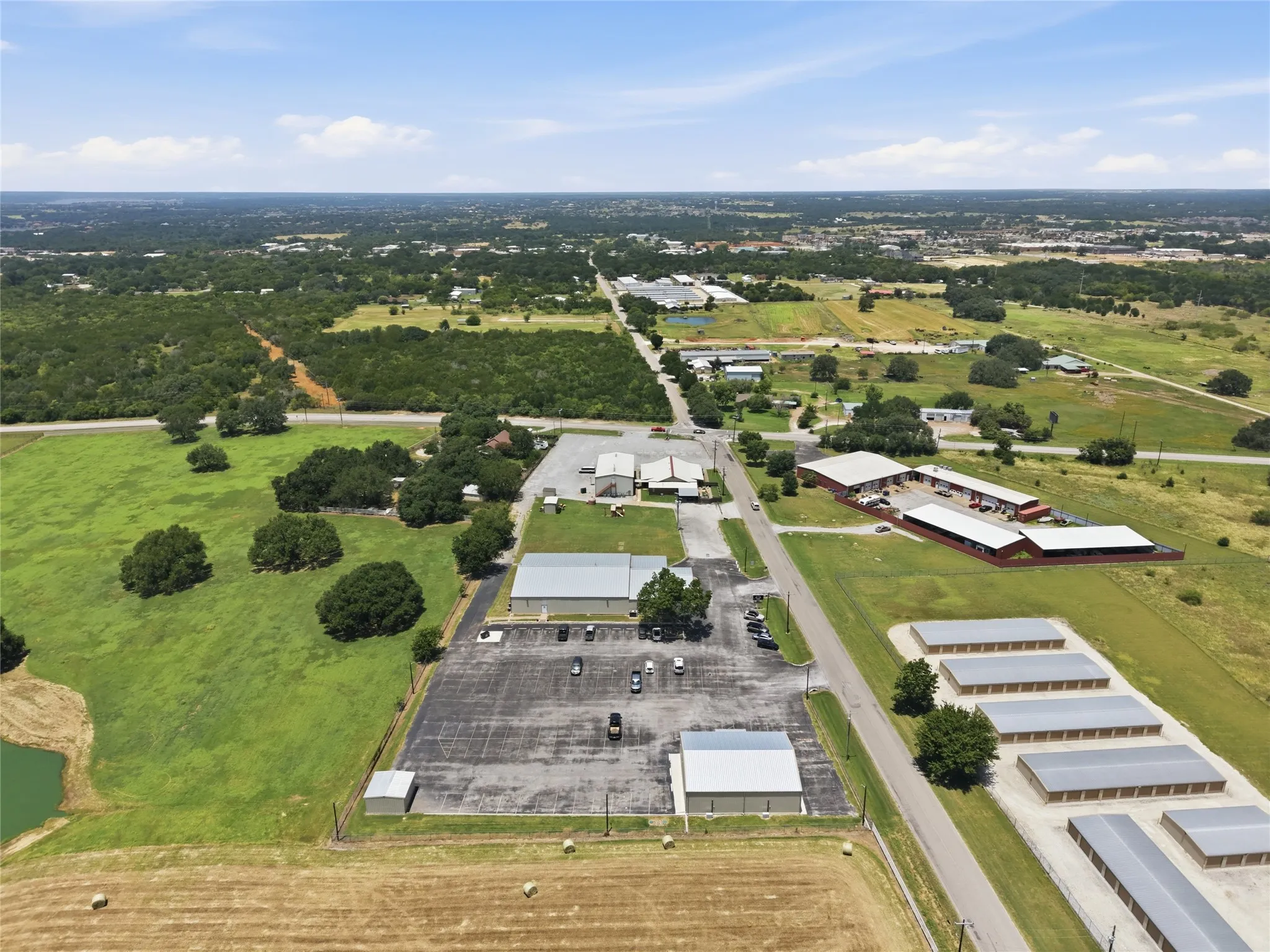 Expansive aerial view showcasing multiple commercial structures, a large paved parking area, and storage units