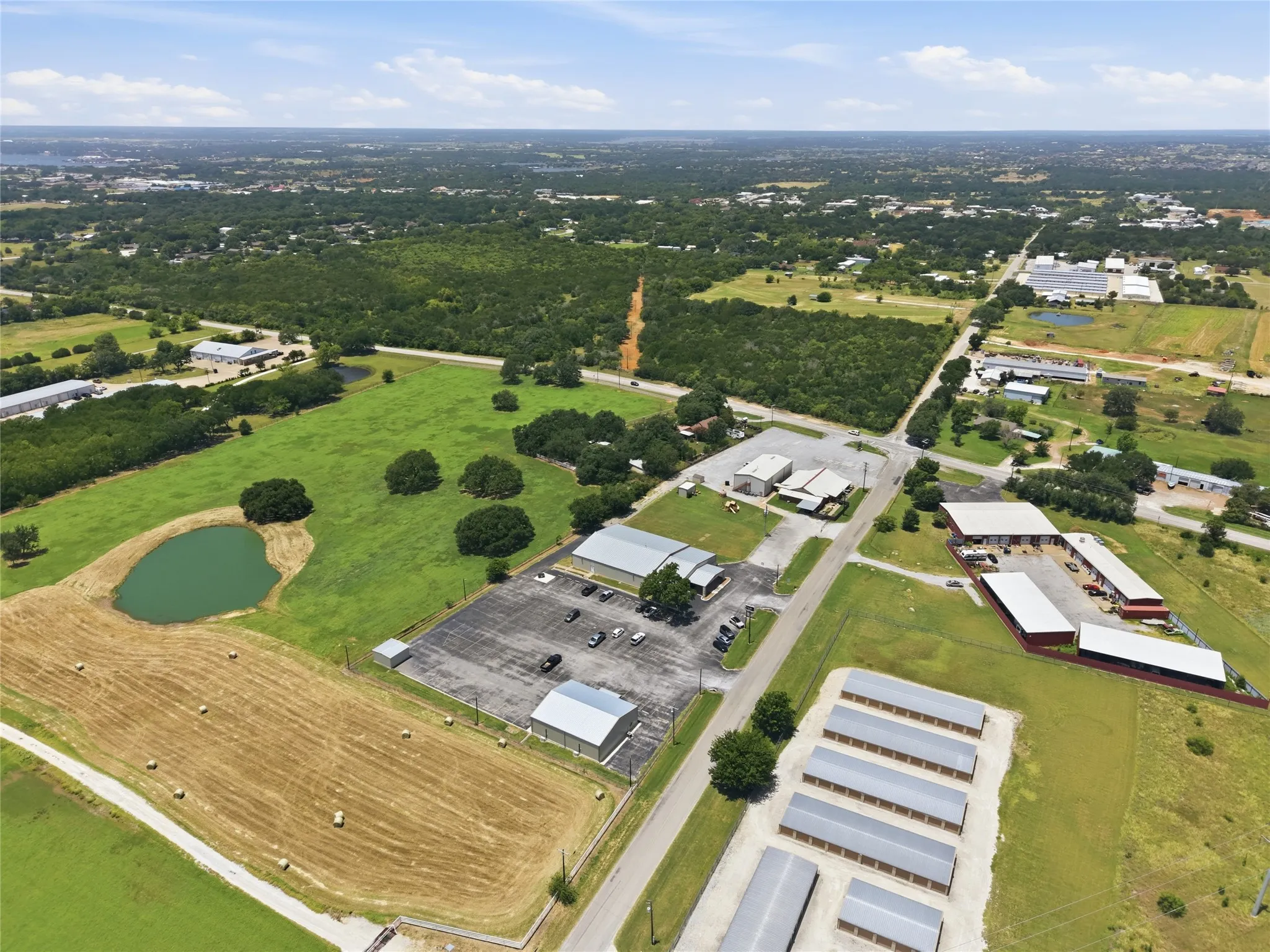 Expansive land parcel featuring open fields, wooded areas, and a pond