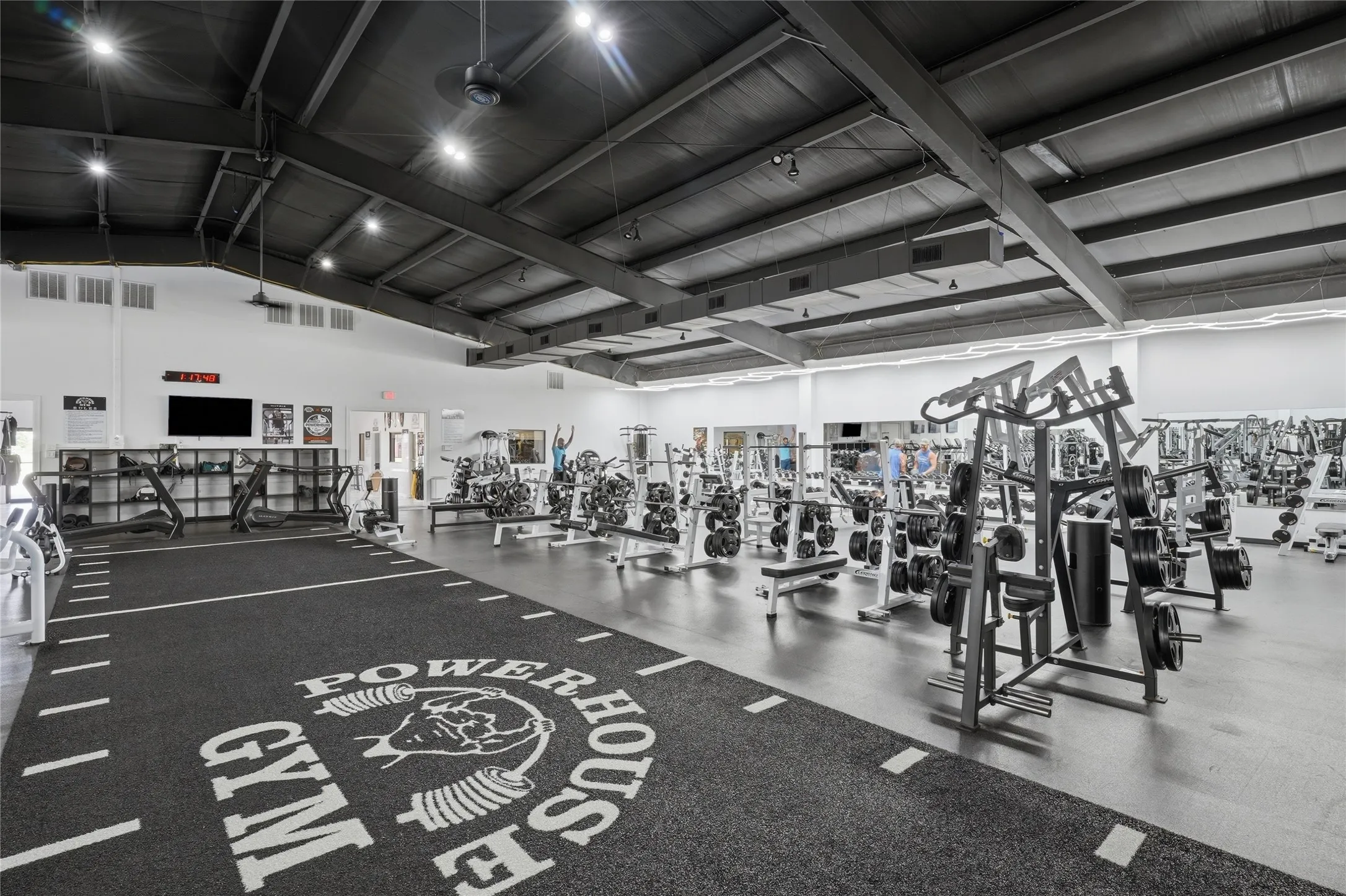 Expansive fitness facility featuring high ceilings with exposed structural elements and track lighting