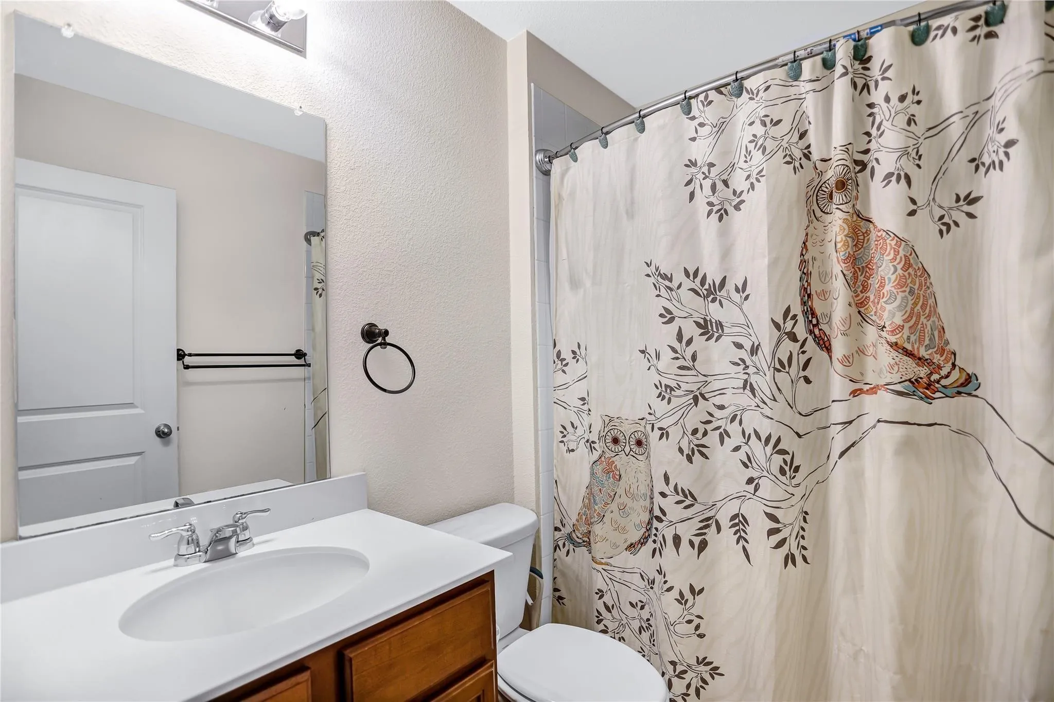 Bathroom featuring a single vanity with wood cabinetry, a white countertop, and a chrome faucet