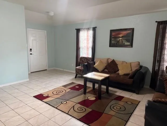 Spacious living area featuring light-toned tile flooring throughout