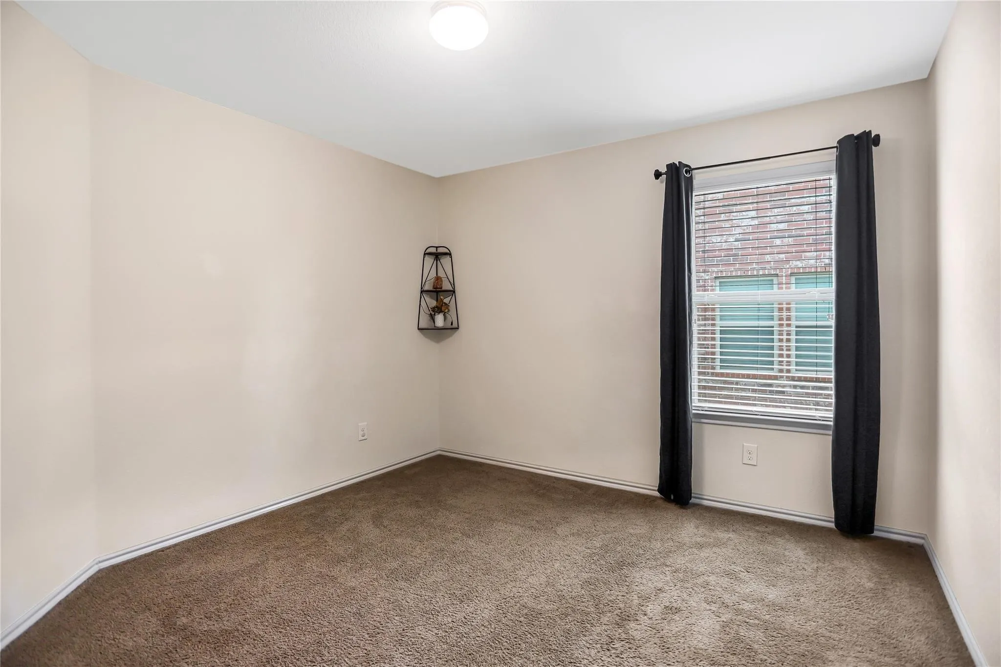 Carpeted room featuring a single window with blinds and a flush mount ceiling light