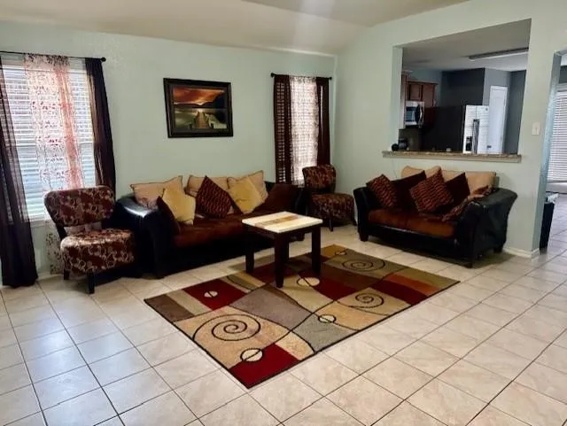 Living space featuring ceramic tile flooring, light-toned walls, and an open pass-through to a separate area