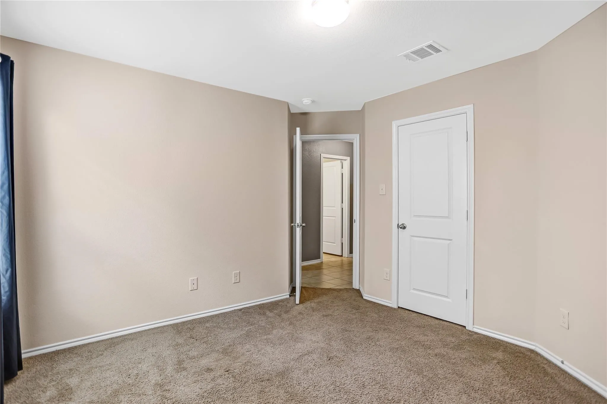 Carpeted room featuring neutral wall tones, white trim, and a flush-mount ceiling light