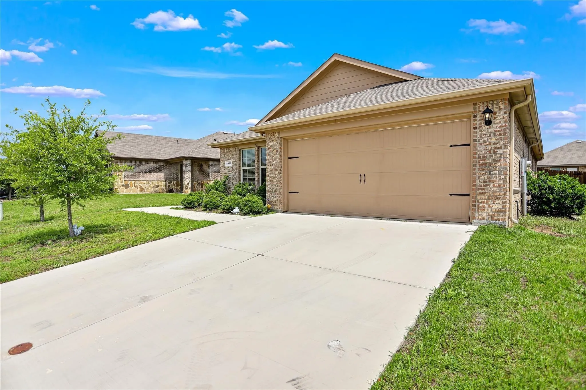 Single-story residence featuring a two-car garage with carriage-style doors, a concrete driveway, and brick and siding exterior finishes