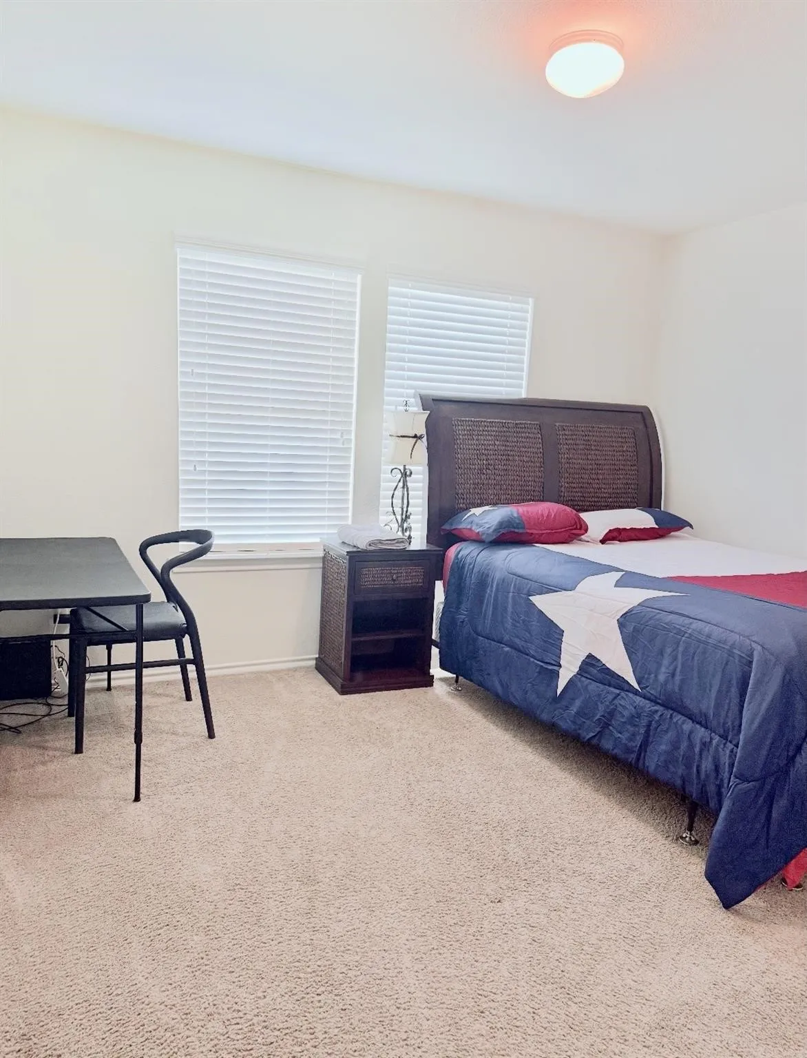 Neutral-toned carpet flooring in a room featuring two windows with horizontal blinds and a flush-mount ceiling light fixture