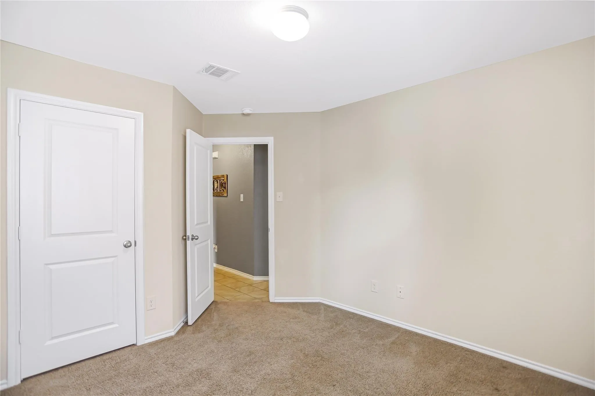 Carpeted room featuring neutral wall paint, white baseboards, and a white ceiling with a flush-mount light fixture