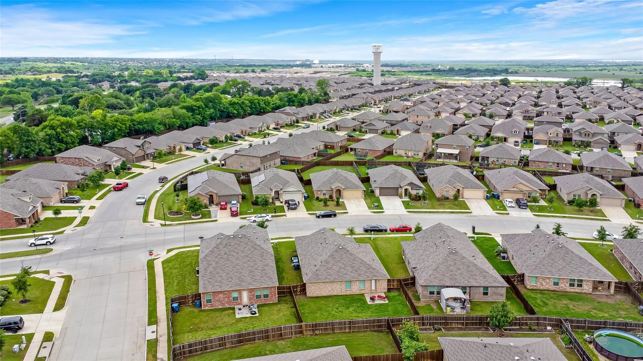 Residential neighborhood featuring a grid-pattern street layout, uniformly sized lots, and a water tower in the distance