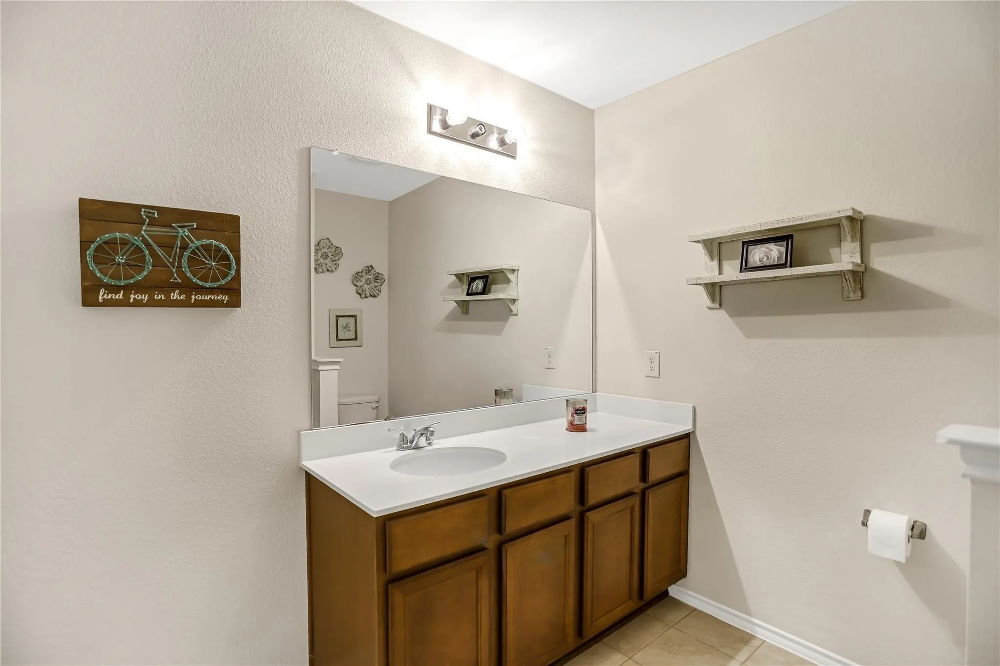 Bathroom vanity featuring a single-basin sink, a white countertop, and wood-finish cabinetry