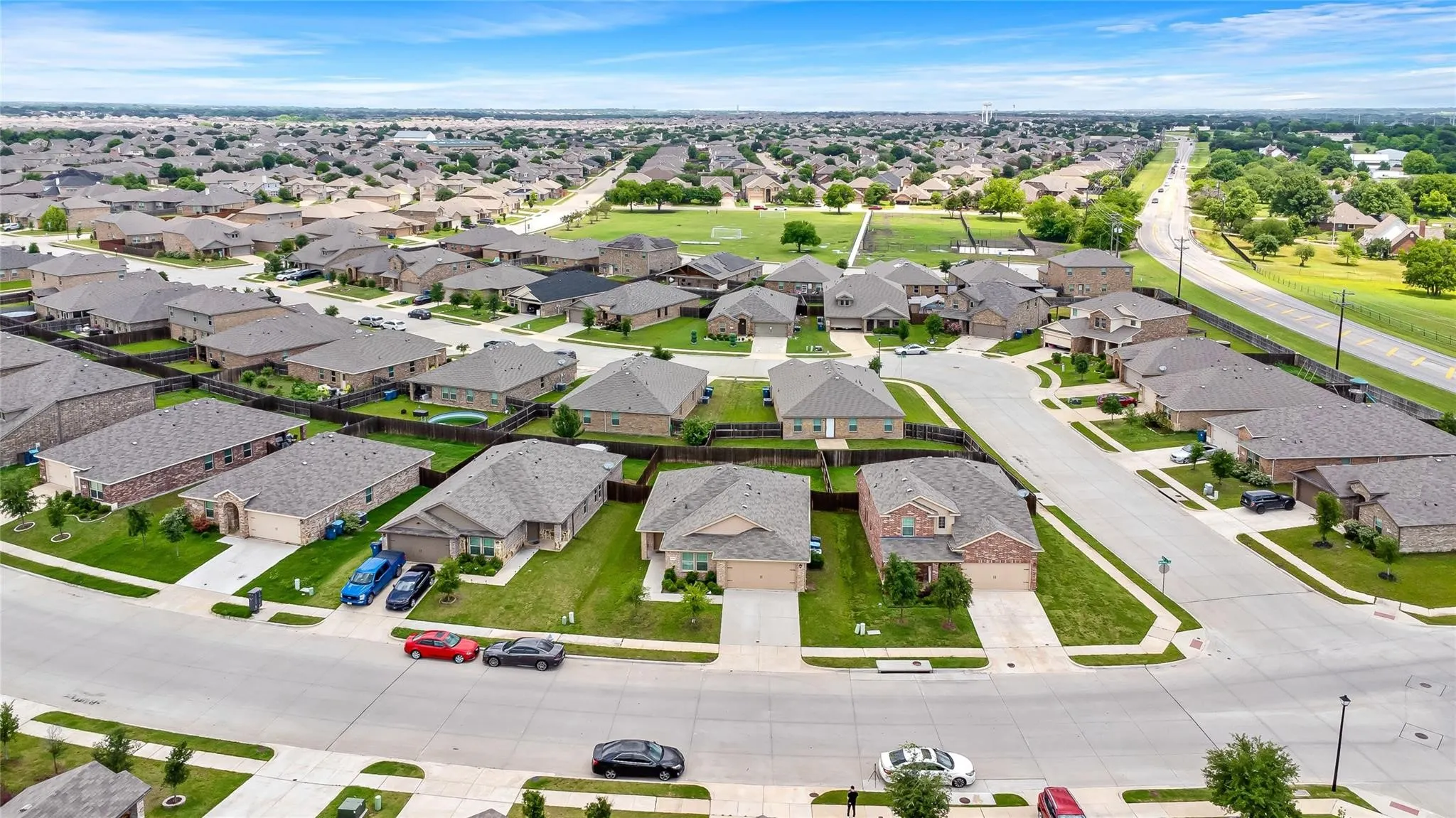 Aerial perspective of a residential neighborhood featuring numerous single-family homes with pitched roofs and attached garages