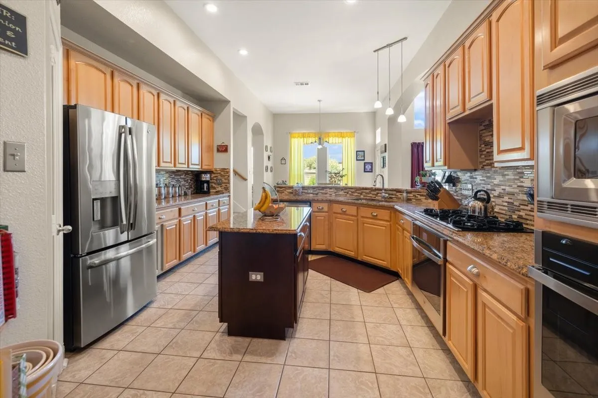 Spacious kitchen featuring extensive light wood cabinetry and granite countertops