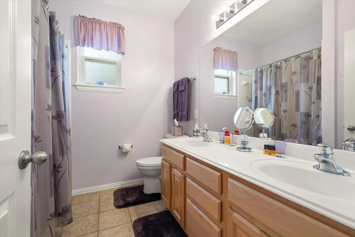 Bathroom featuring a dual vanity with integrated sinks, wood-finish cabinetry, and chrome fixtures