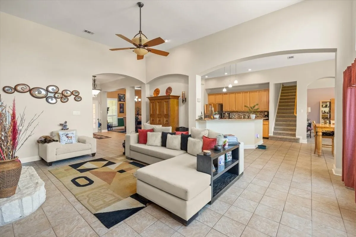Spacious living area featuring vaulted ceilings and a ceiling fan