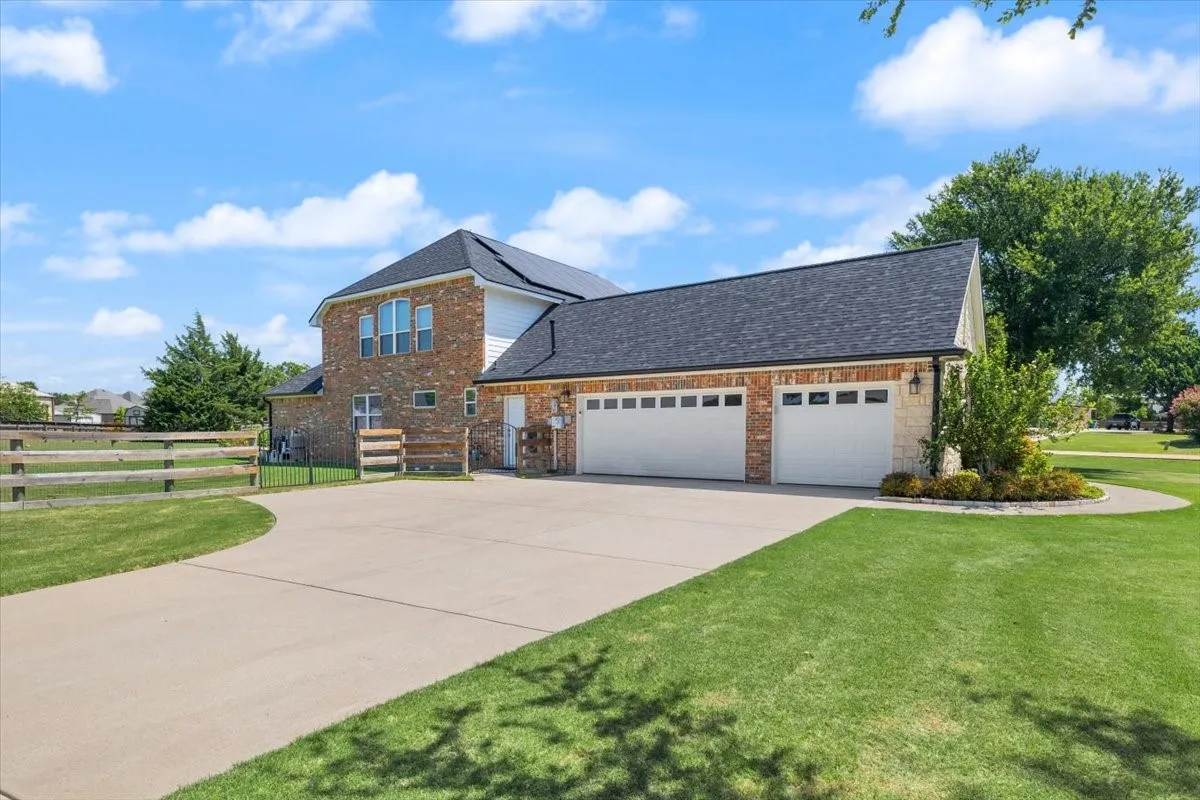 Two-story residence featuring brick and siding exterior, a multi-car garage with white doors, and a concrete driveway
