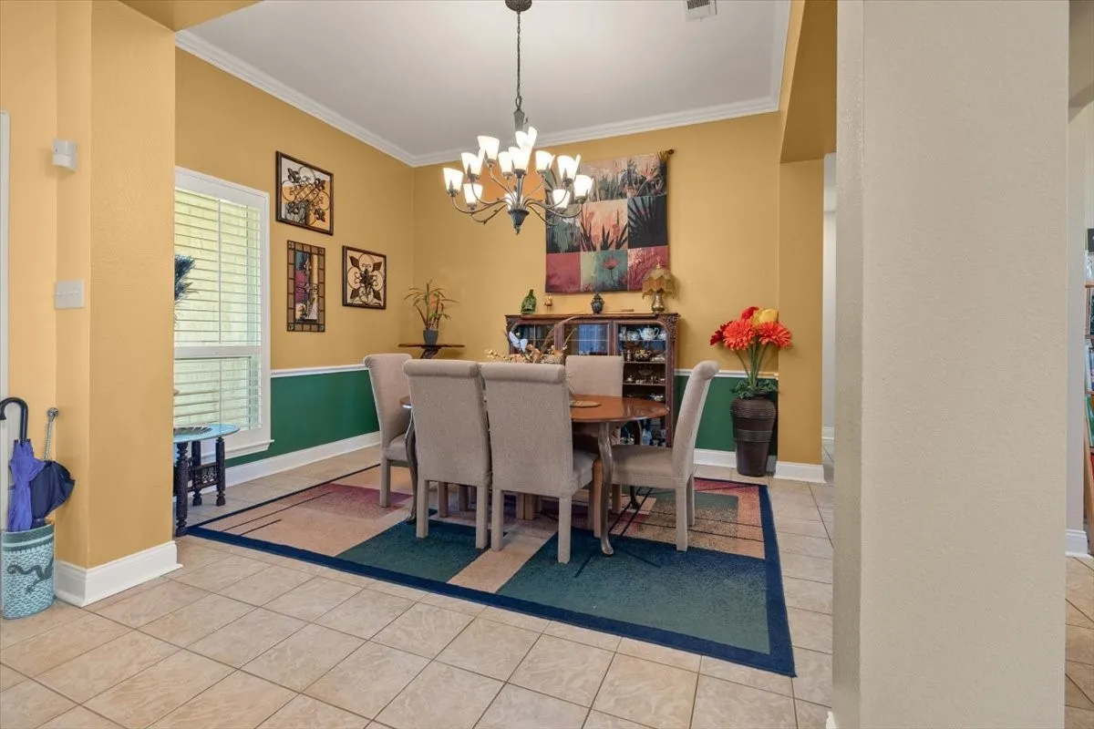 Dining area featuring tiled flooring, crown molding, and a chandelier lighting fixture