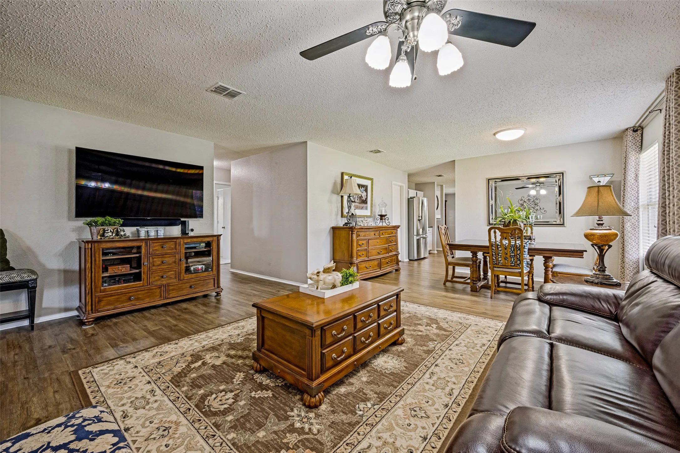 Spacious open-concept living area features luxury vinyl plank flooring, ceiling fan.