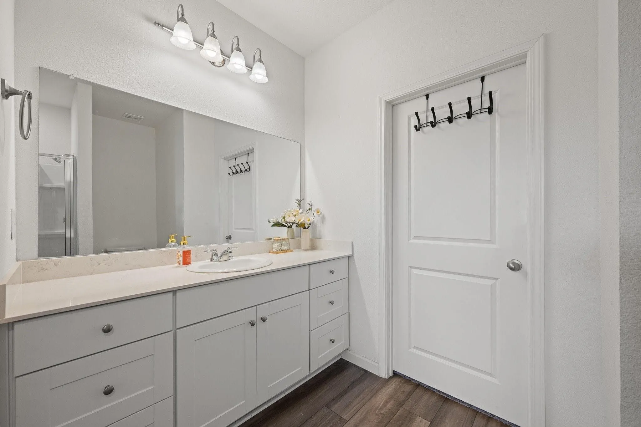 Sleek bathroom vanity featuring dual sinks, gray cabinetry, modern fixtures, and bright overhead lighting.
