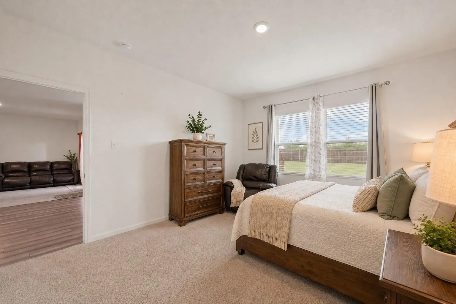 Virtually Staged — Second primary bedroom angle with a warm, neutral palette, wood furnishings, and generous space for a full bedroom suite.
