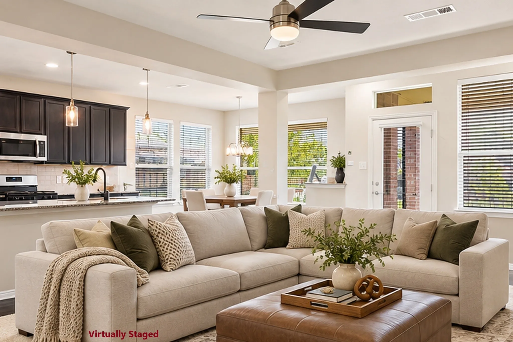 Open-concept living space featuring a neutral-toned sectional arrangement, leather ottoman coffee table, and abundant natural light from multiple windows