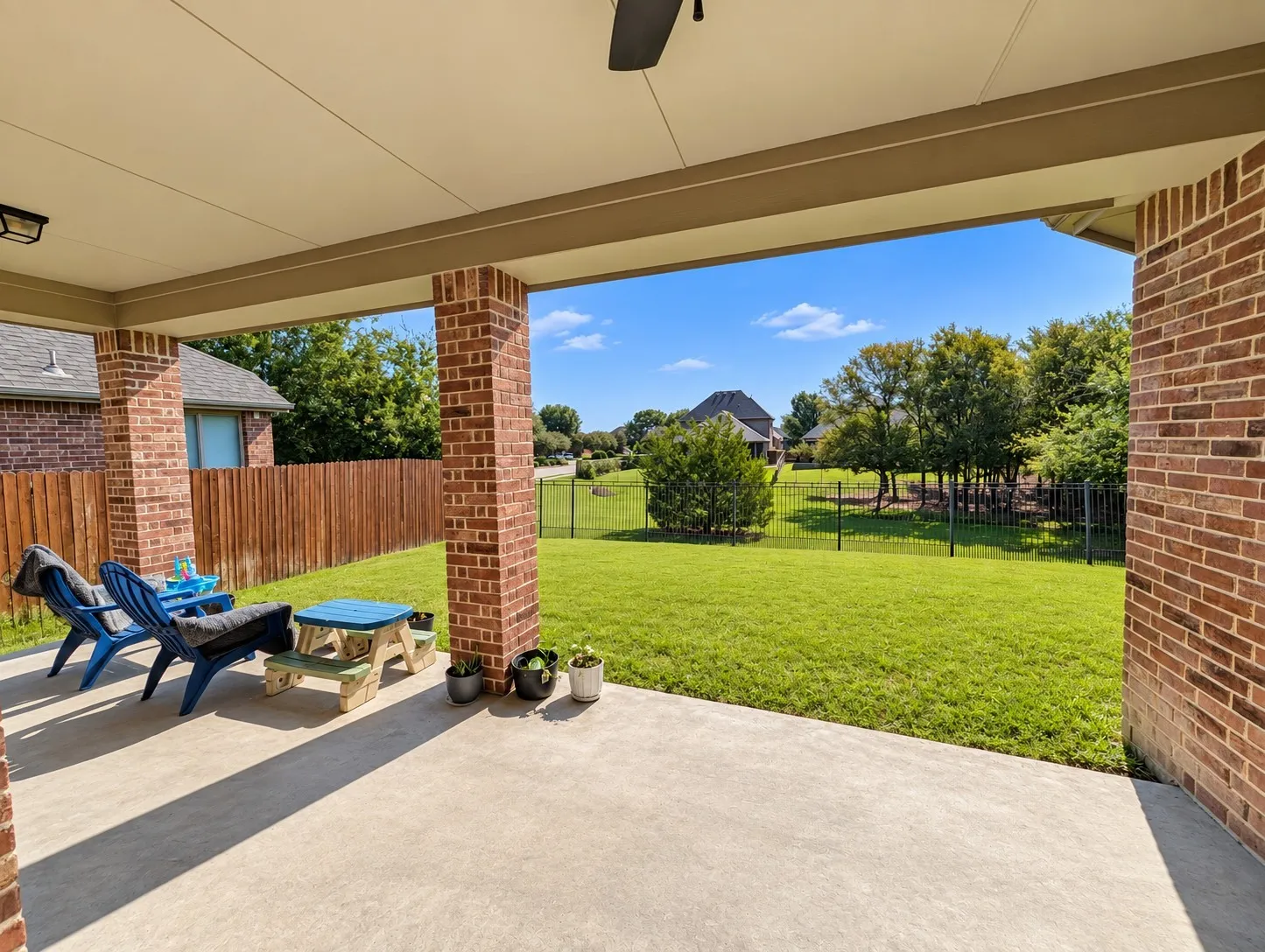Covered patio with a concrete surface, brick columns, and a ceiling fan