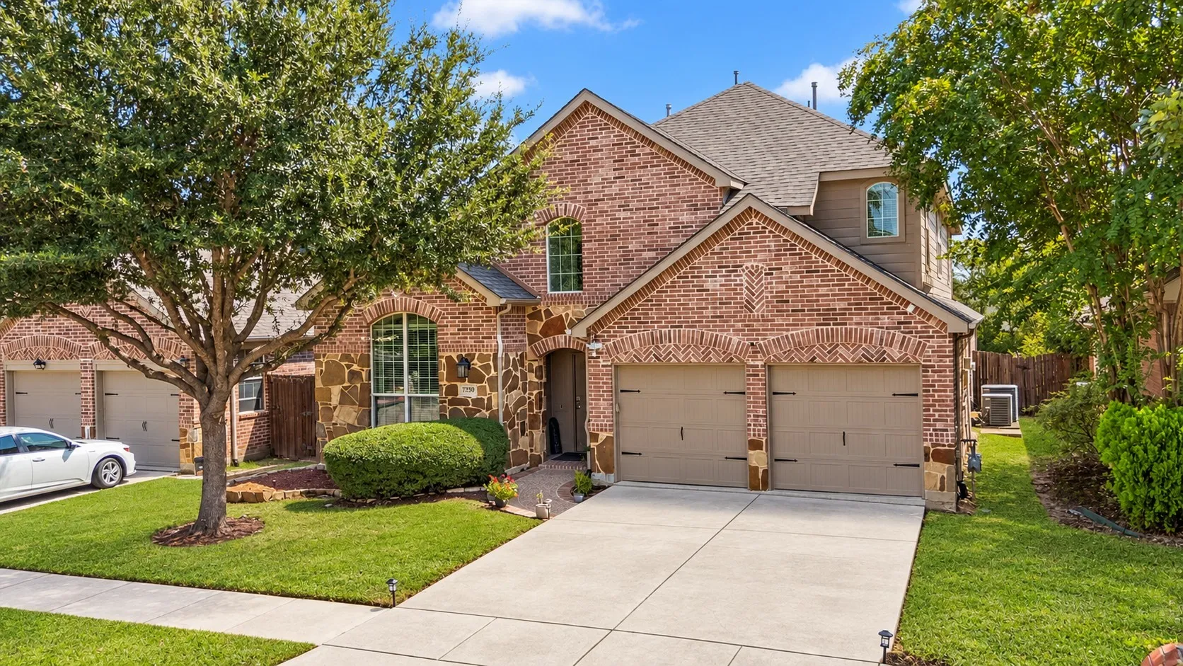 Brick and stone facade with arched window details, a two-car garage, and a concrete driveway