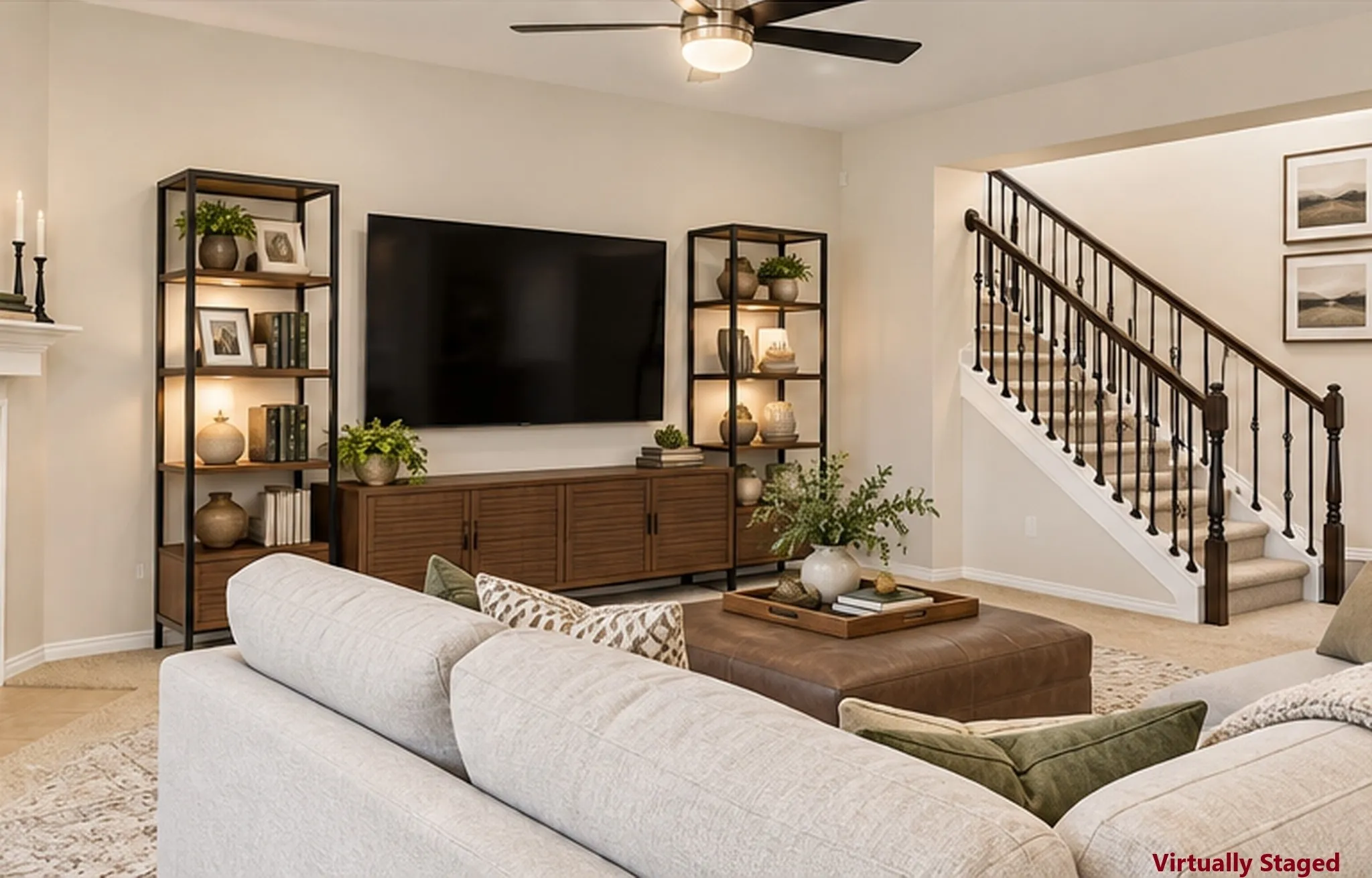 Recessed lighting, ceiling fan with integrated light, carpeted staircase with dark wood handrail and black balusters, built-in shelving units, and a media console